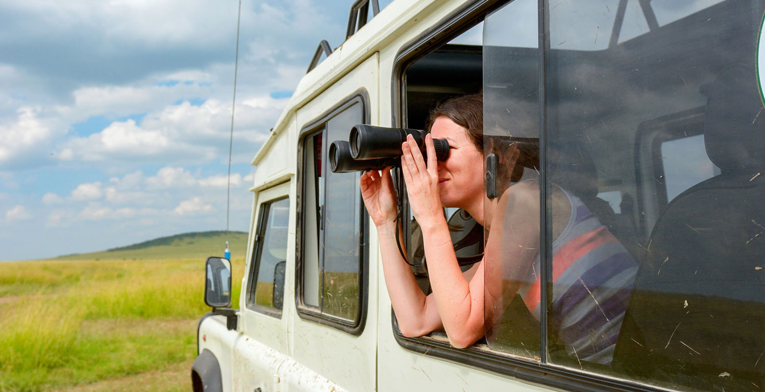 Woman using binoculars on safari