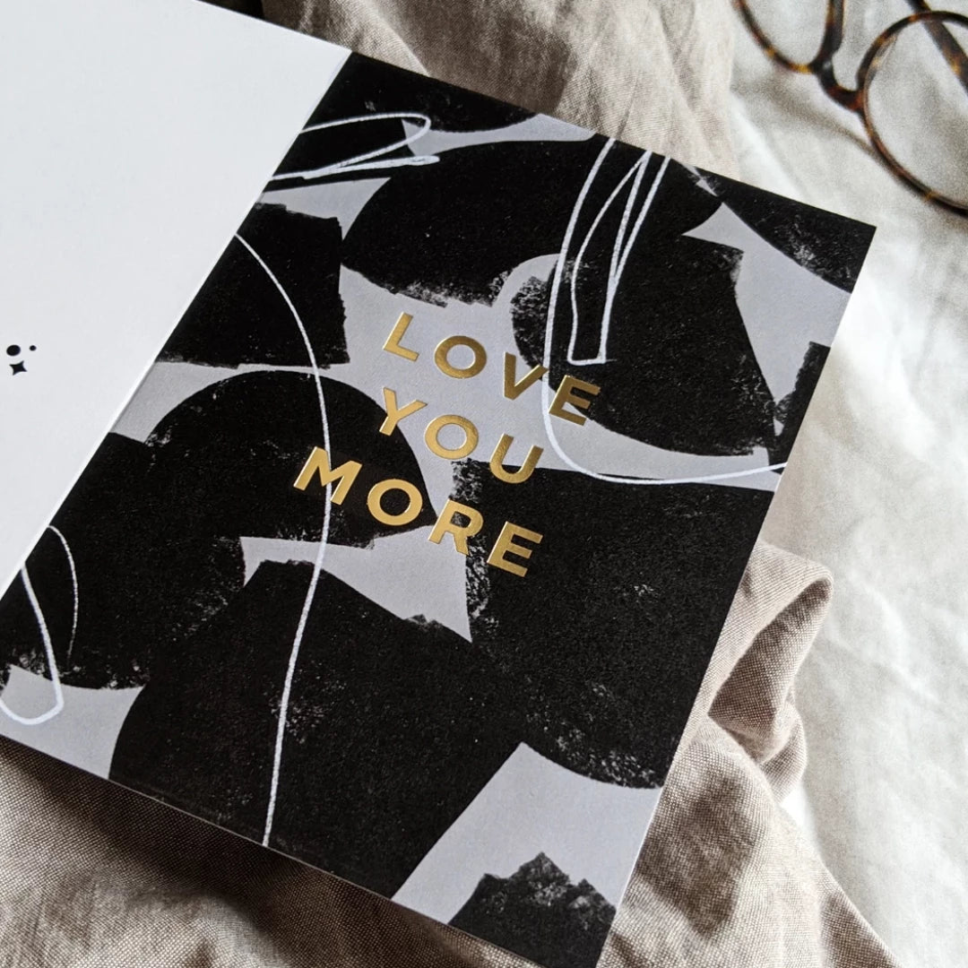 black and white card that says love you more in gold