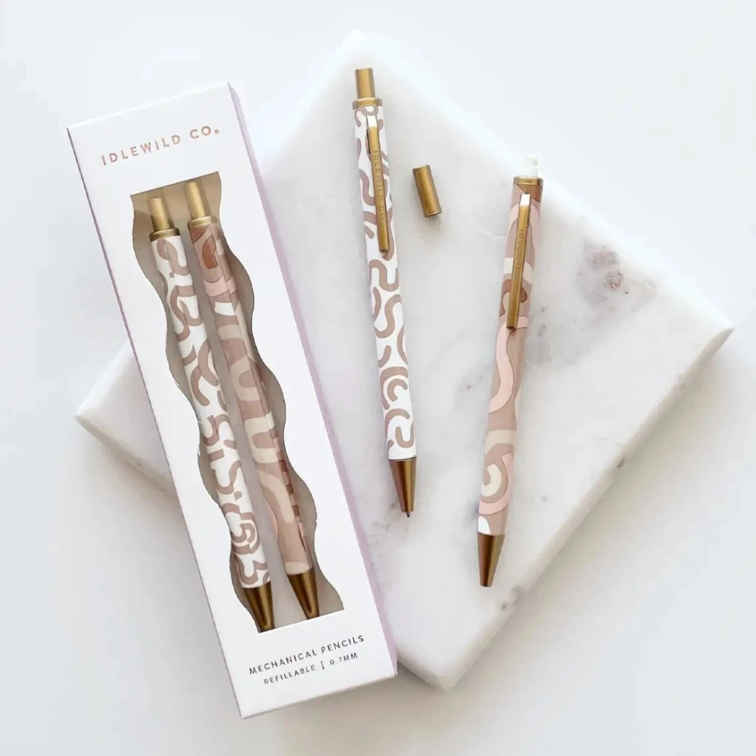 set of two mechanical pencils one is white with neutral coloured squiggles and gold decal and the other is neutral with pink and neutral coloured squiggles with gold decal