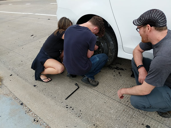 Post-festival excitement during our road trip: Sam and Dana attach a spare tire while Jon supervises