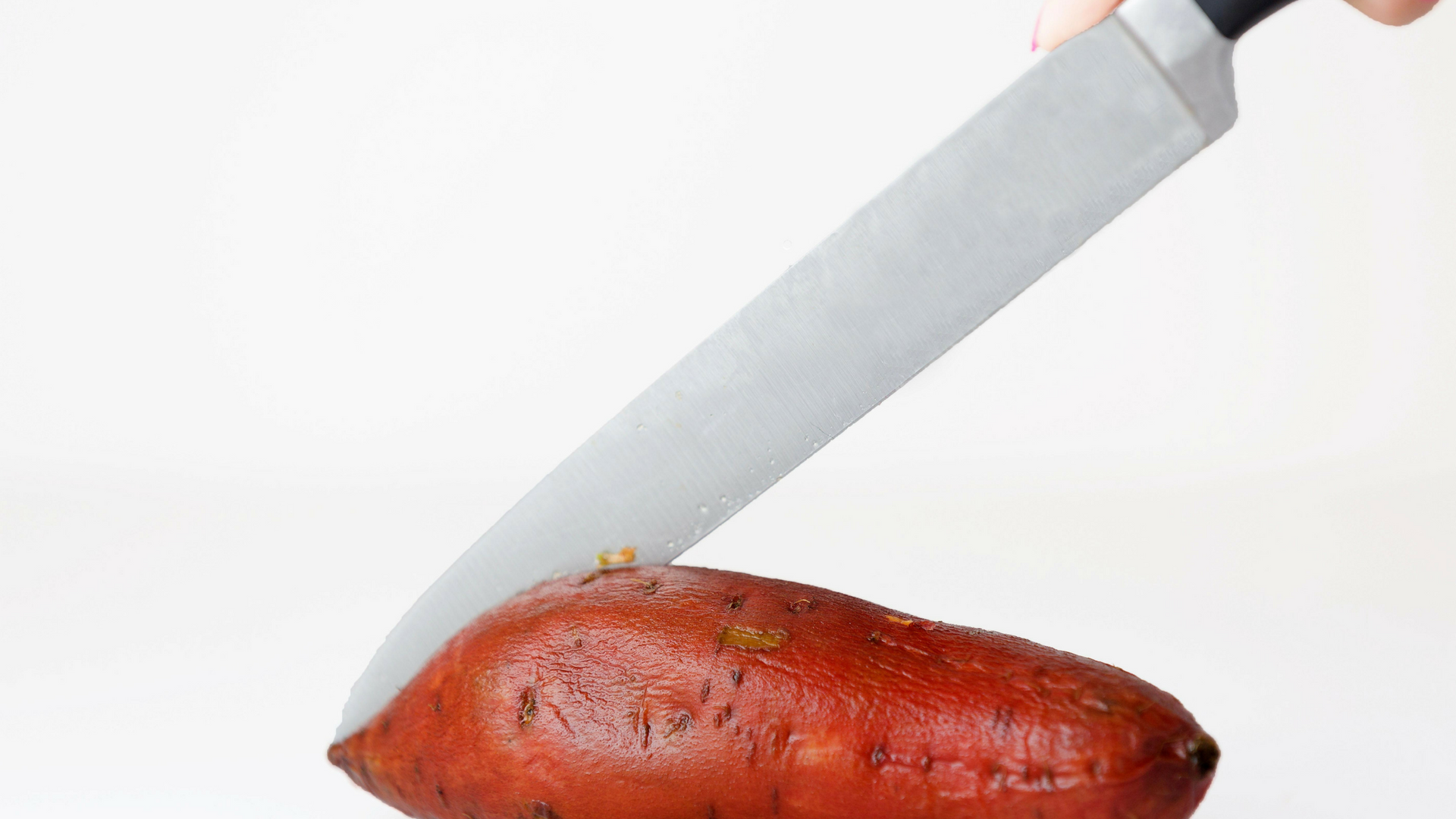 Knife slicing sweet potato
