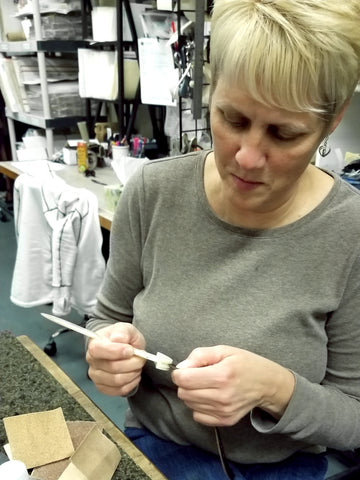 event guest burnishing the edges of the strap for the bracelet she's making at the Leather & Laughs event