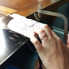 Cutting out geometric shapes from bronze sheet for new jewelry collection