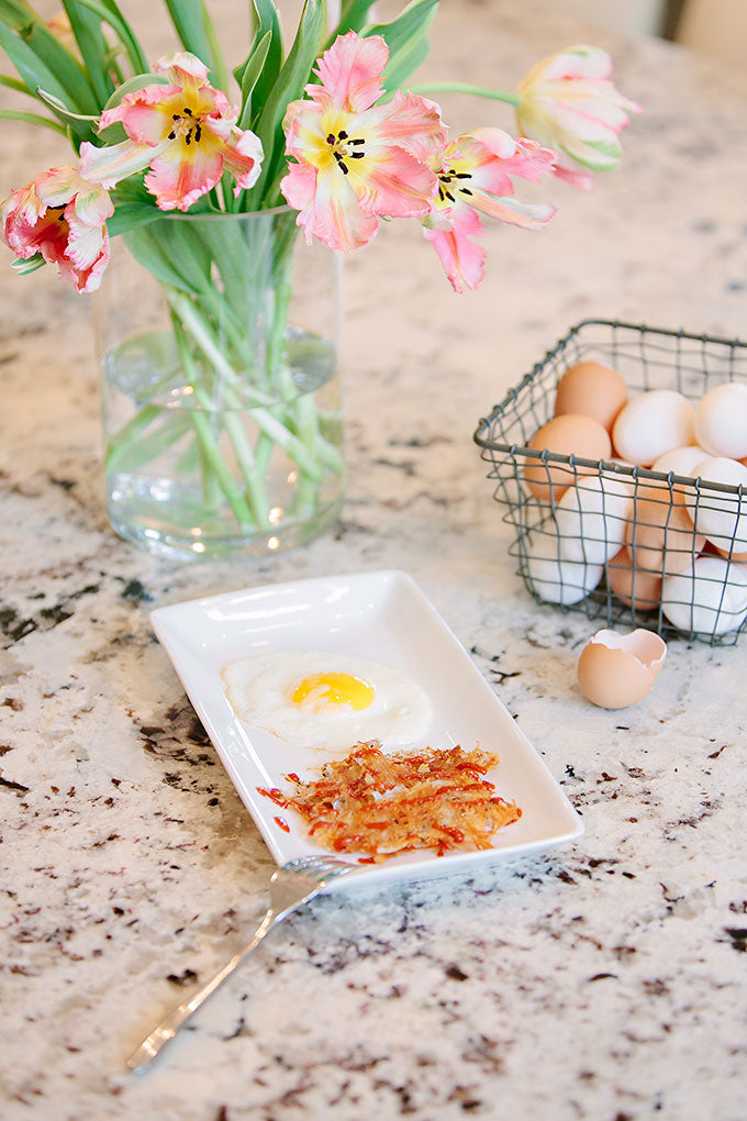 Hash brown on a plate with egg next to flowers