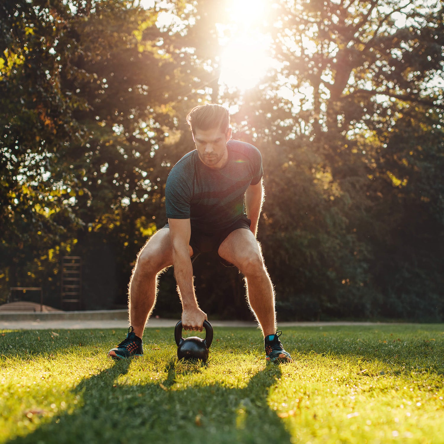 Man lifting kettlebell weight on grass
