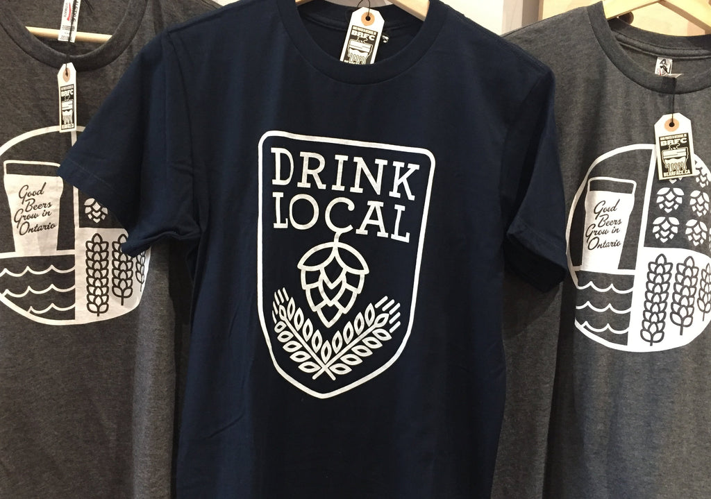 Navy Drink Local t-shirt by Kitchener-based BRFC hanging between two Good Bears Grow in Ontario t-shirts