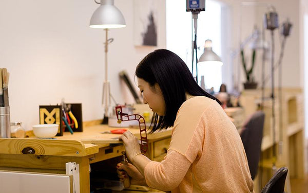 Kara Yoo creating handmade jewellery at a desk in her Vancouver studio