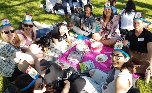 Group of people sitting in a circle, playing games and enjoying a picnic at a Queers for Dinner event