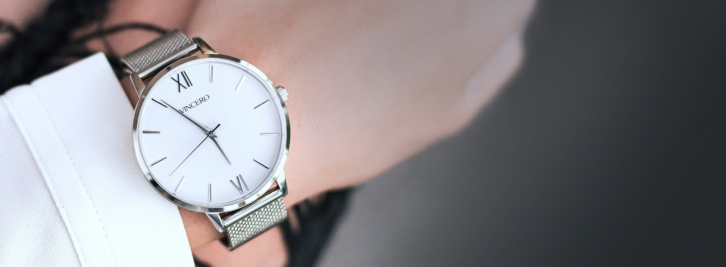 Close up of white and silver watch with silver mesh strap