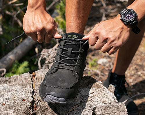 a man ties the laces of his black boots.