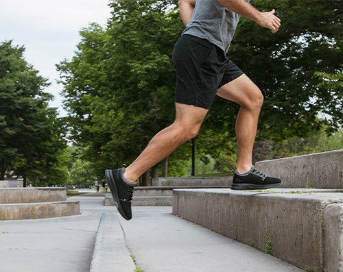 A man wearing KURU ATOM athletic sneakers running up a set of steps