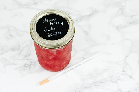 wide mouth pint mason jar full of strawberry freezer jam topped with a black chalkboard label