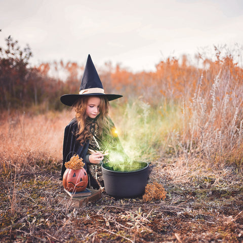 Girl in a witch costume stirring a boiling cauldron source: Unsplash