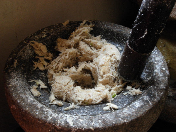 Someone using a mortar and pestle to crush arrowroot into a powder
