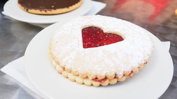 A round biscuit made with Arrowroot Powder with a heart shaped strawberry jelly patch in the middle.