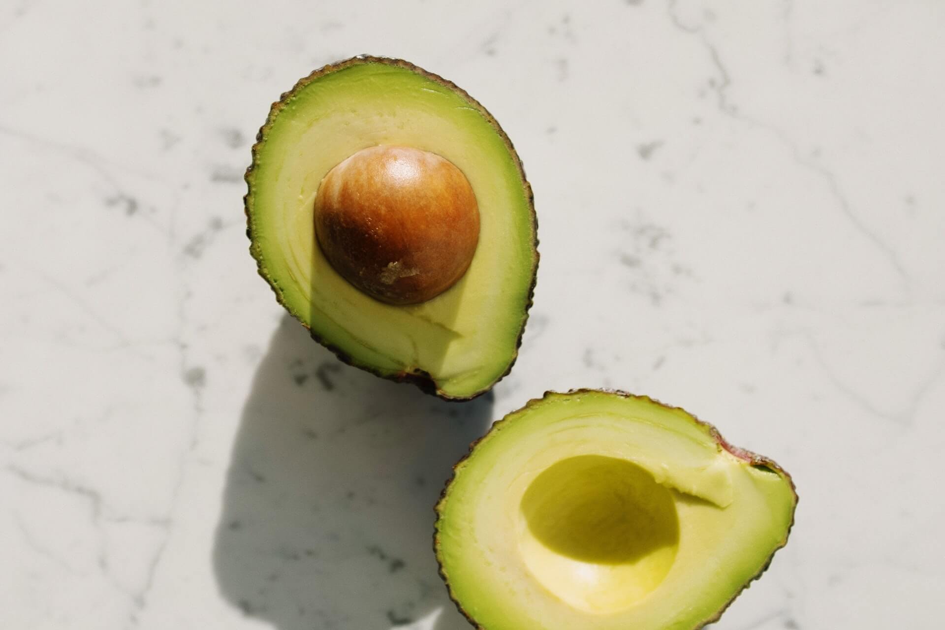 Avocado cut open on marble countertop