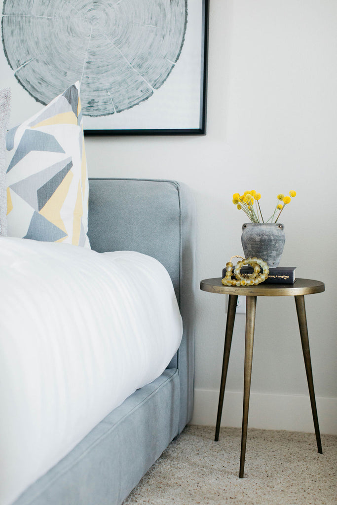 greige design shop + interiors grey and yellow bedroom with brass table grey upholstered bed