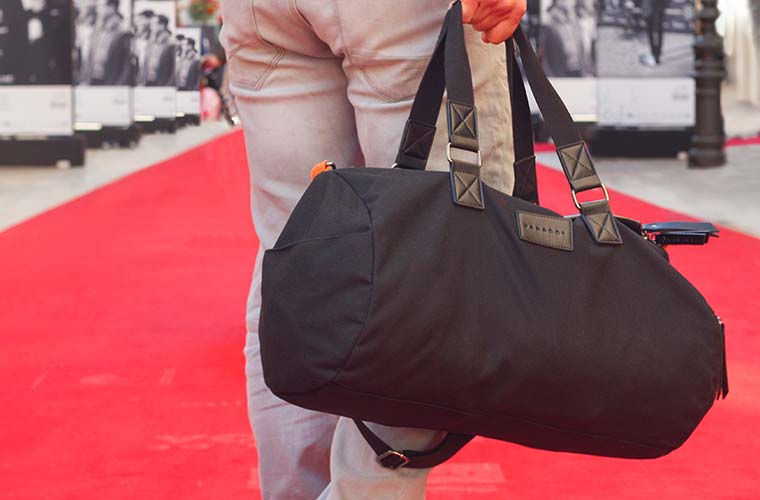 Vanacci Roma Duffel Bag Held By Man On Red Carpet, Walking Away