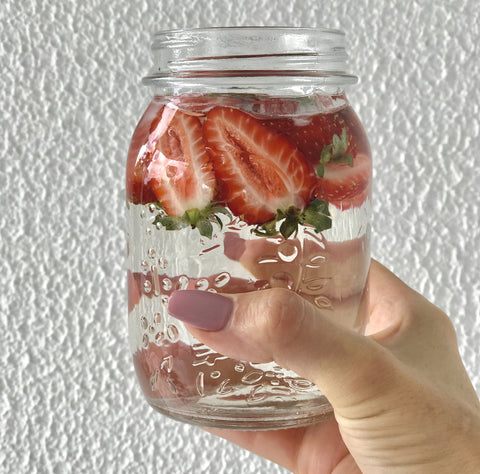 Strawberries floating in a jar with water