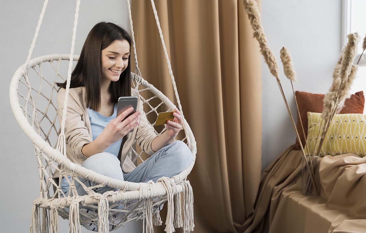 mulher sentada fazendo compras parceladas no cartão de crédito pelo celular