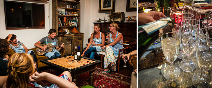 A corporate team gathered around a carrom table playing guitar and drinking wine.