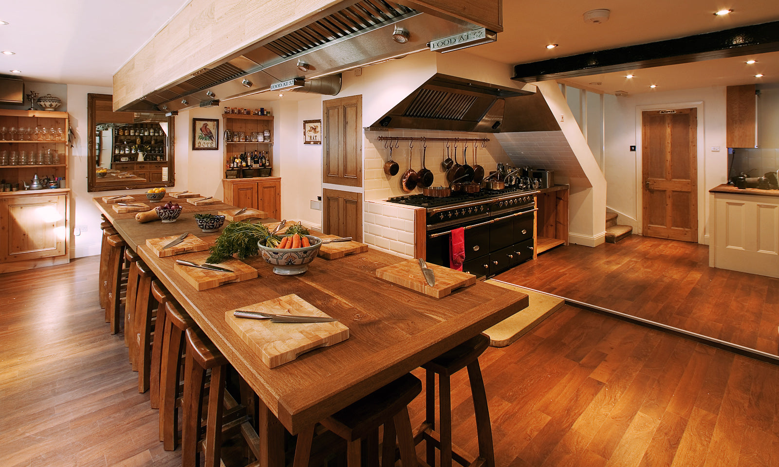 The Food at 52 kitchen with a view of its oak banquet table and gas stoves.