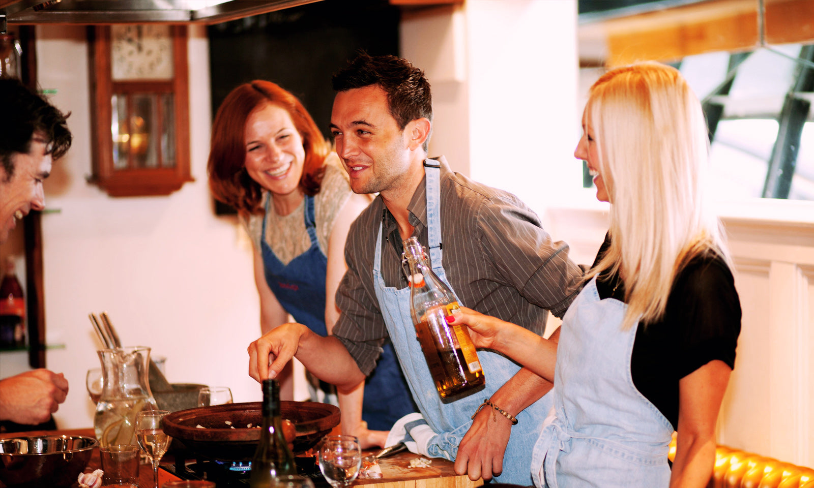 A group of people laughing and cooking around our oak banquet table.