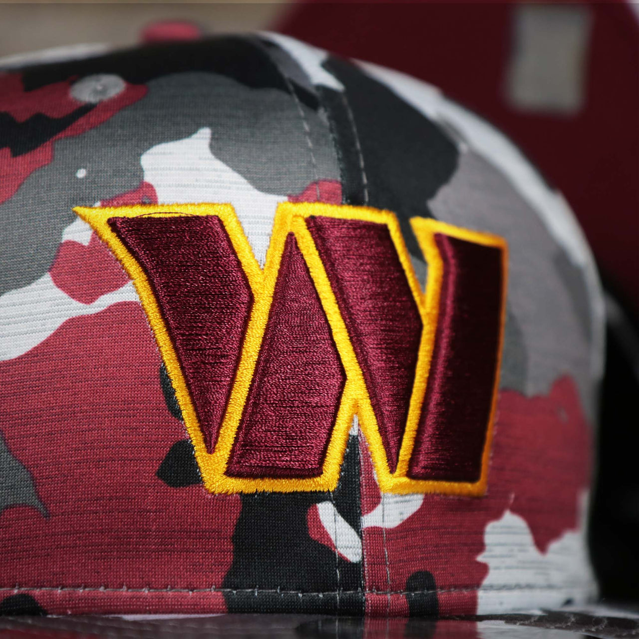 The Commanders Logo on the Washington Commanders NFL OnField Summer Training 2022 Camo 9Fifty Snapback | Burgundy Camo 9Fifty