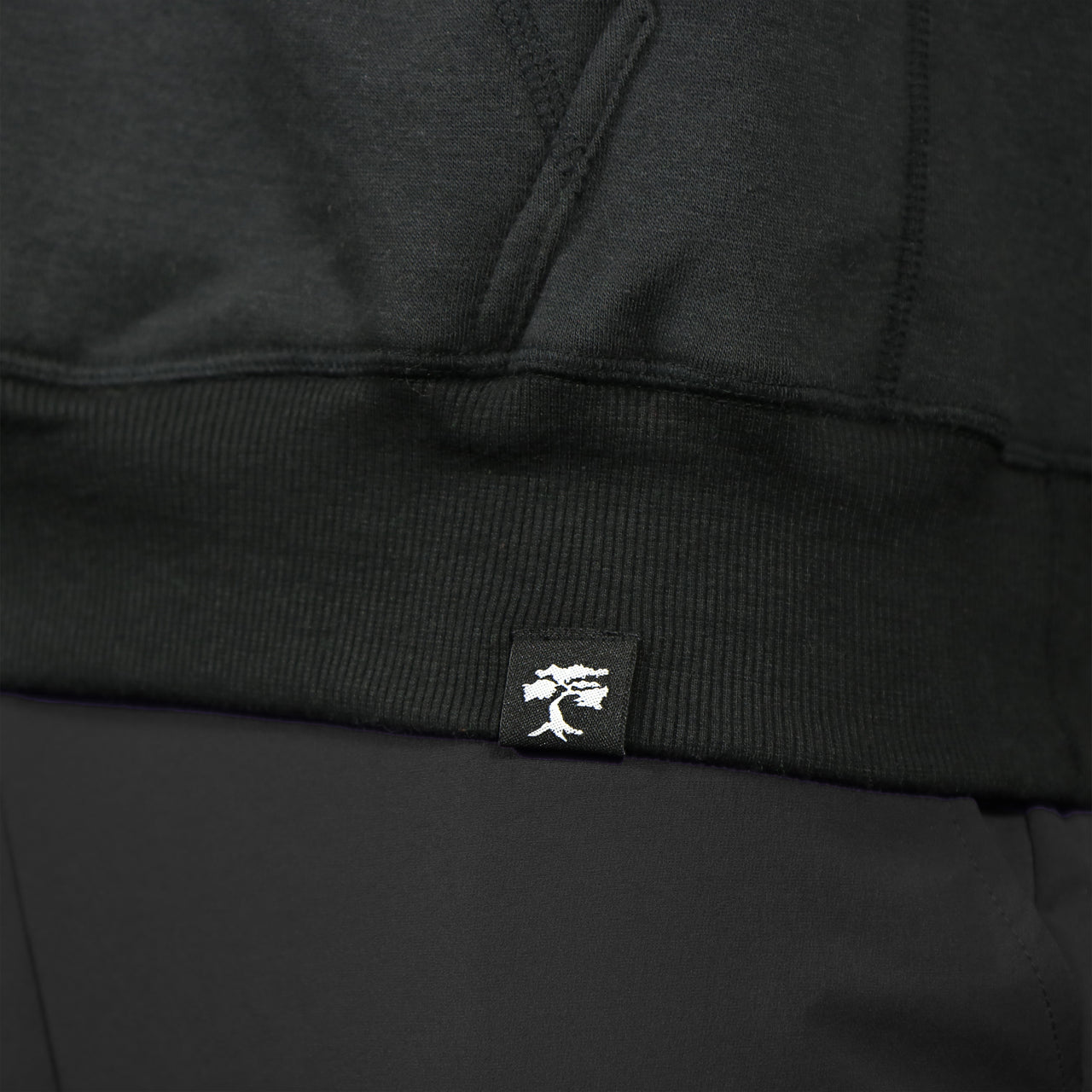 bonsai tree logo on the Jet Black Unbasic Fleece Stash Pocket Sunset Park Tapered Pullover Hoodie | Fleece Black Hoodie