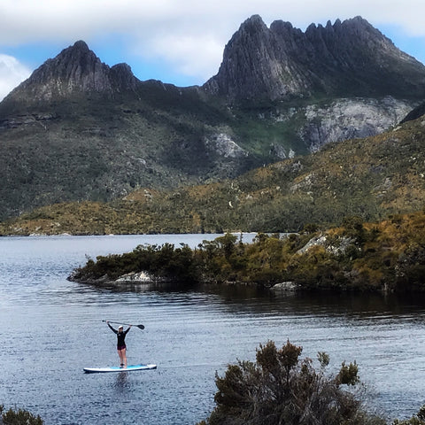 woman on paddle board poses on dove lake infant of Cradle Mountain