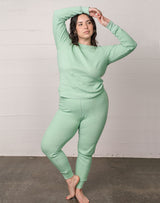 Woman wearing organic waffle thermal pajama top and organic waffle thermal bottom in sage