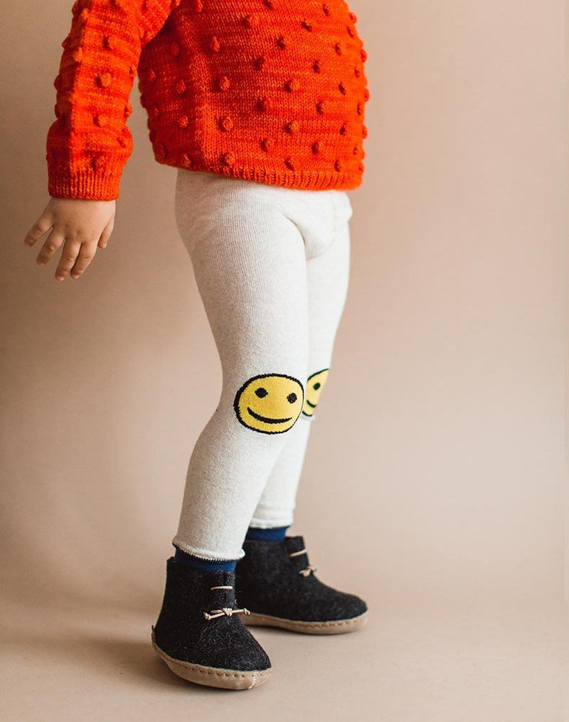 Baby wearing red popcorn sweater, smiley leggings and charcoal Glerups wool baby boots