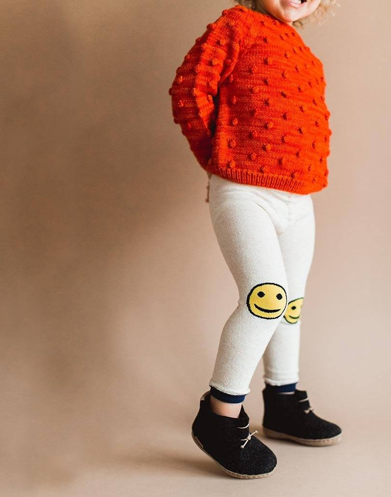 Baby showing off his red popcorn sweater, smiley leggings and charcoal Glerups wool baby boots