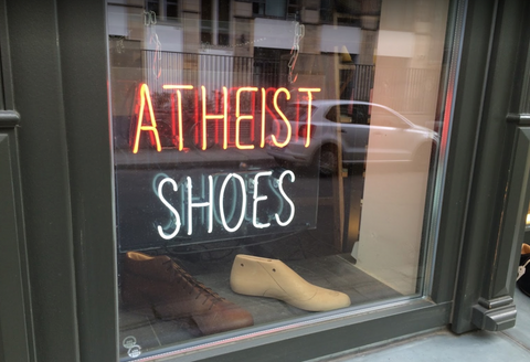 Atheist shoes neon storefront sign with window display.