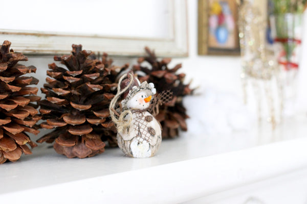 snow man decoration on fireplace mantle, pine cones christmas decorations