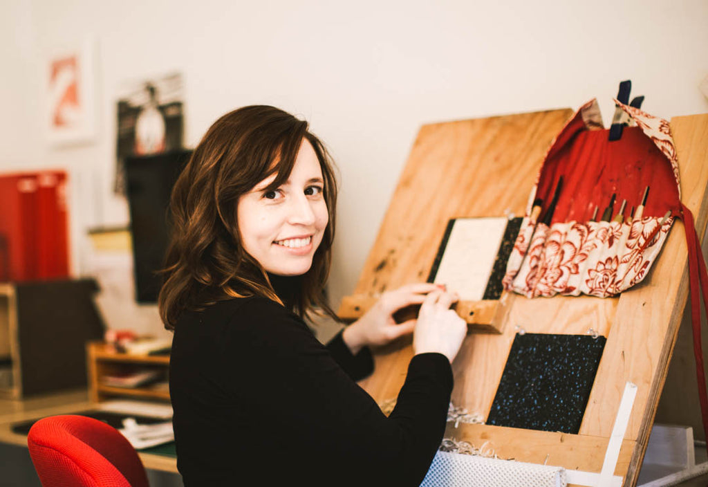 A photo of printmaker and illustrator Rachel Kroh at her carving bench in her studio