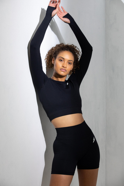 Fitness Model poses with her arms up wearing Doyoueven Black Hyperflex Long Sleeve and Shorts