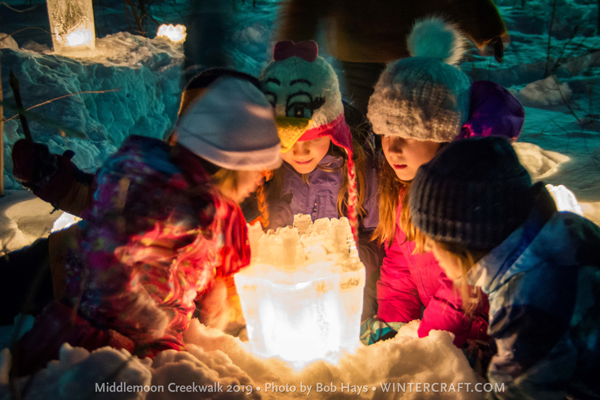 Kids staring into a sand castle bucket ice lantern