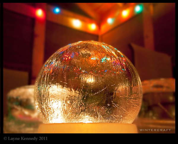 Wintercraft Globe Ice Lantern with party lights in the background