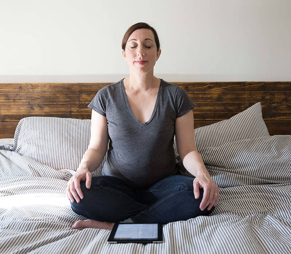 pregnant woman meditating on bed