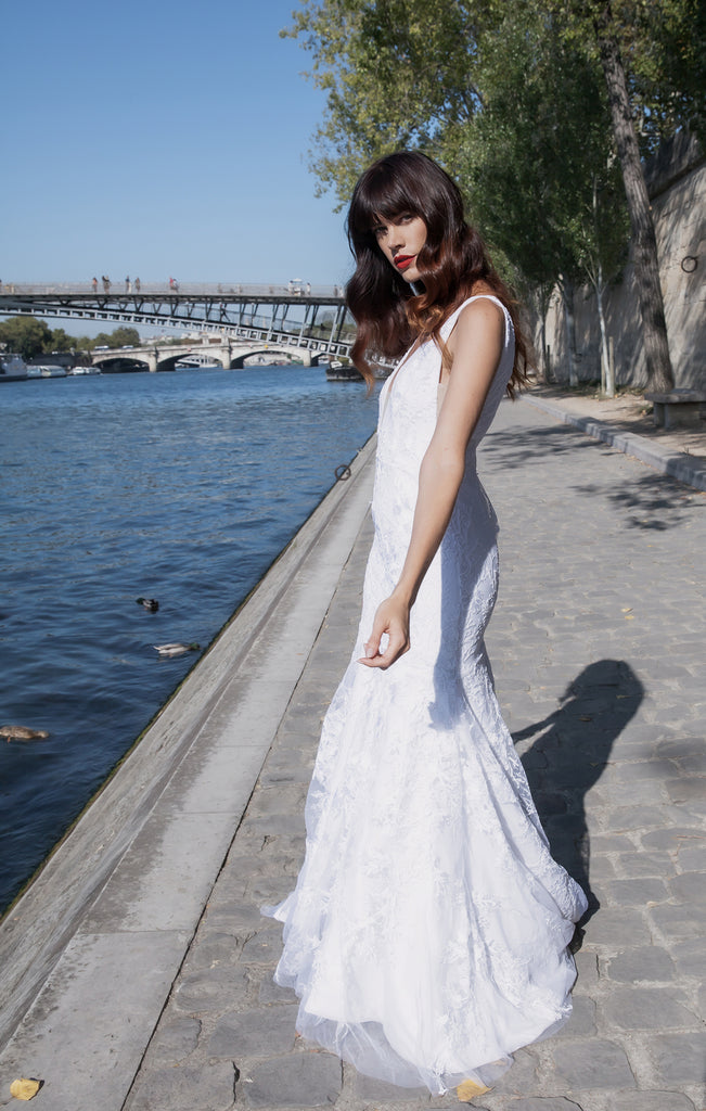 model standing next to the River Seine wearing a wedding dress while twirling on a sunny day.