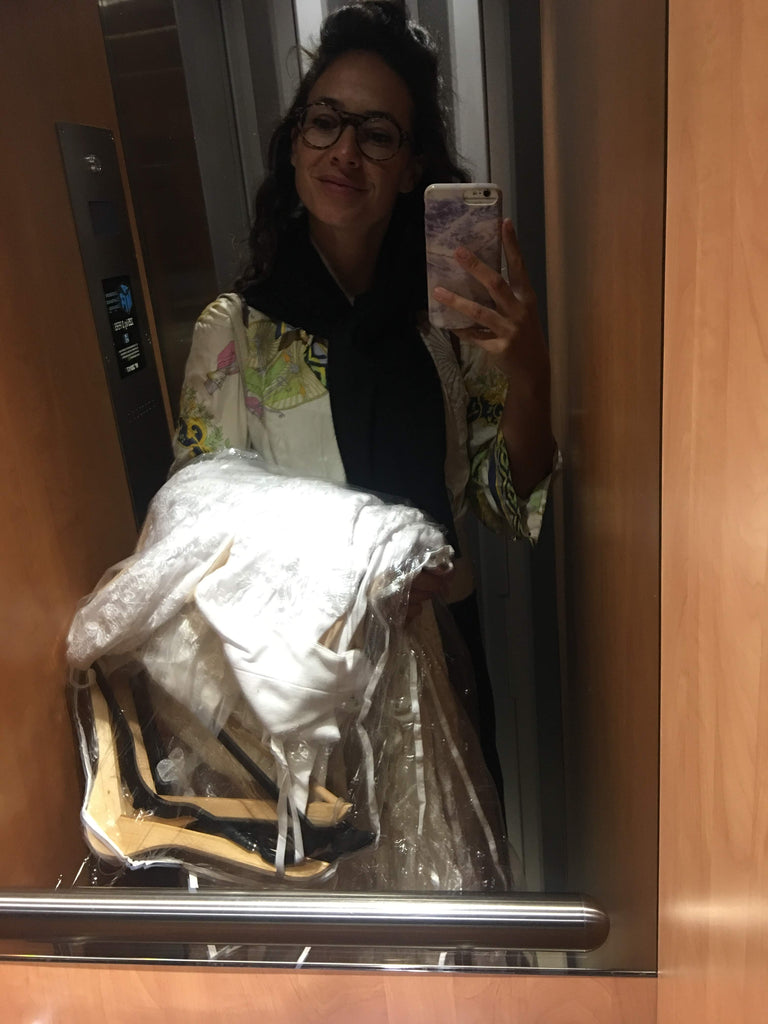 Hrissa, designer of Elika In Love, holding wedding dresses in a small elevator in Paris.