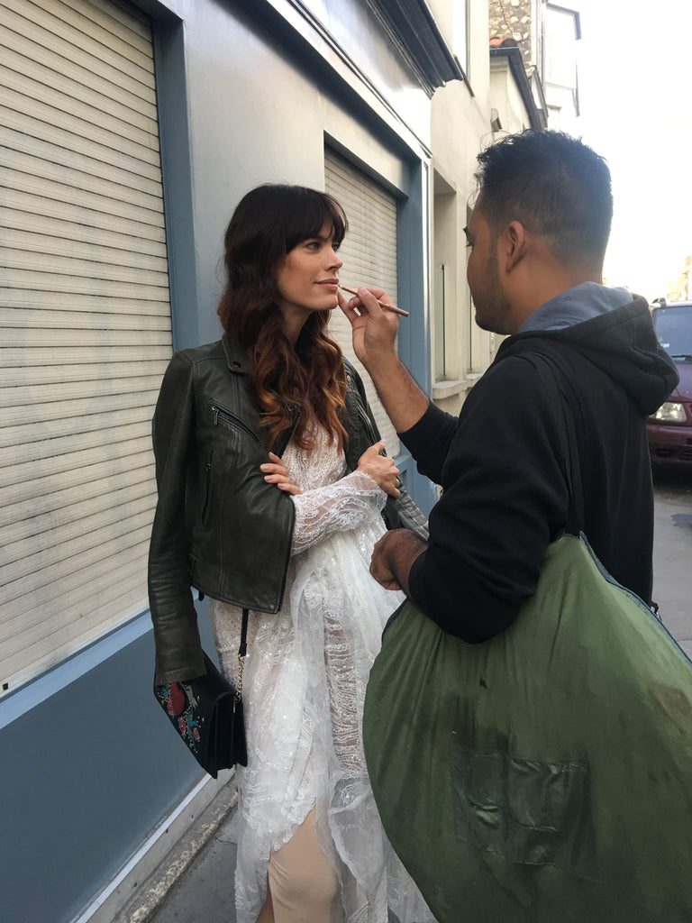 make up artist doing models makeup in wedding dress while standing.