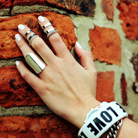 hand with rings and bracelet on a brick wall