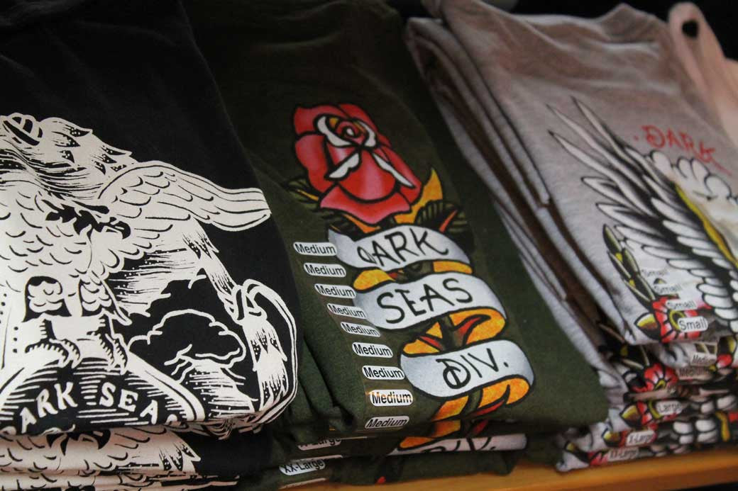 assortment of Dark Seas t-shirts on table