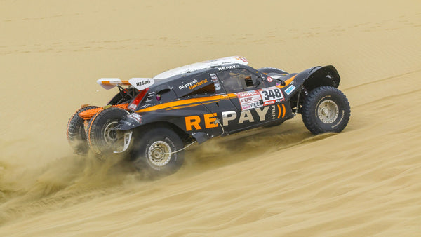 Dakar Rally car driving through sand in Saudi Arabia
