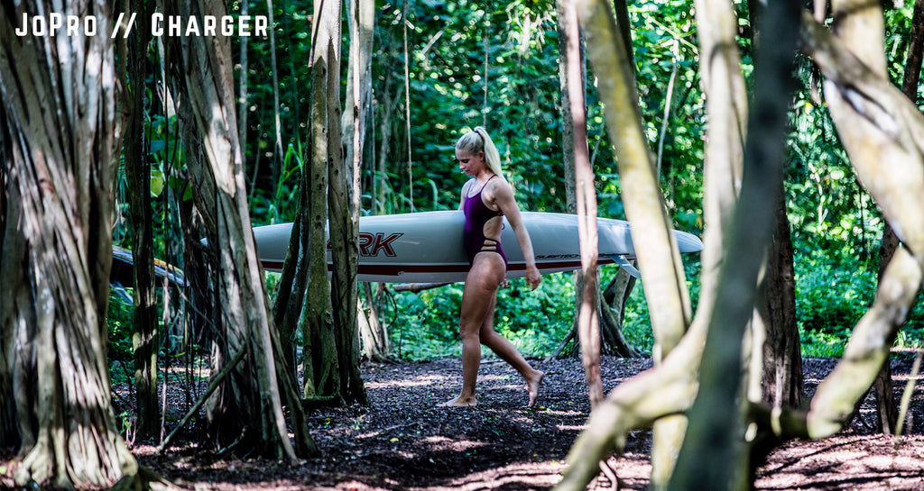 Charger Carter and friend walking with surfboards through a forest