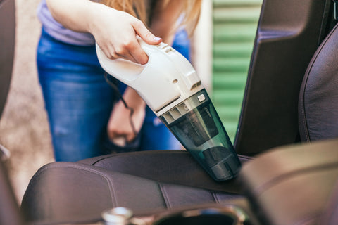 woman cleaning vehicle with car vacuum