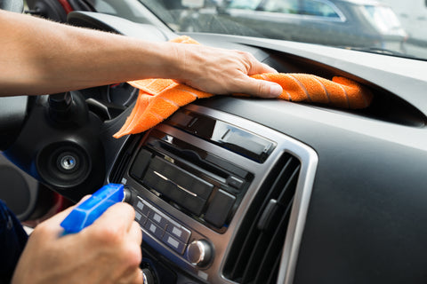 person cleaning car dashboard
