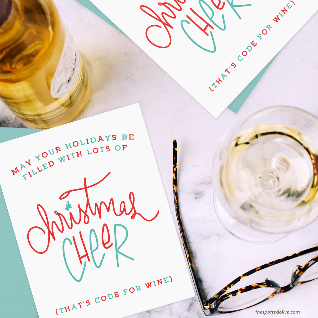 Hand Lettered Christmas Cheer Holiday Card on marble surface with glass of wine, wine bottle and eyeglasses
